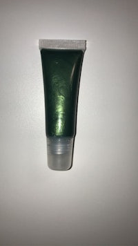 a tube of green liquid makeup sitting on a white surface