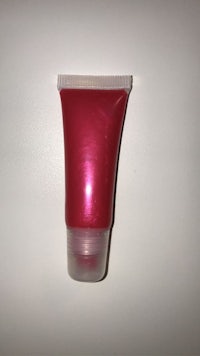 a tube of red lipstick on a white surface